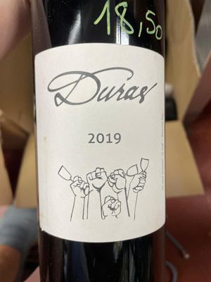 someone is holding a bottle of wine with a drawing on it