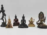 five bronze figurines of buddhas sitting on a white surface
