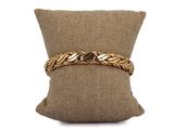 a close up of a pillow with a gold bracelet on it