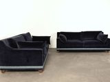 two black velvet sofas and a chair in a white room