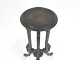 une table ancienne en métal noir, avec un plateau rond et des pieds