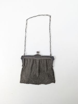 un vieux sac à main suspendu à une chaîne sur un mur blanc