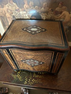 une petite boîte en bois posée sur une table, avec un tableau derrière