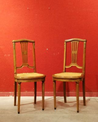 une paire de chaises en bois adossées à un mur rouge dans une pièce