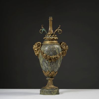 un grand vase en bronze orné de motifs en marbre vert, posé sur un socle