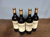 four bottles of wine are lined up on a wooden table