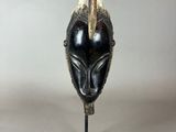a close up of a black and gold mask on a metal stand