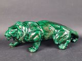 un gros plan sur une statue verte représentant un lion, sur fond gris
