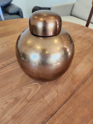 a gold vase sitting on a wooden table in a living room
