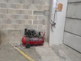 a small air compressor sitting on the ground in front of a brick wall