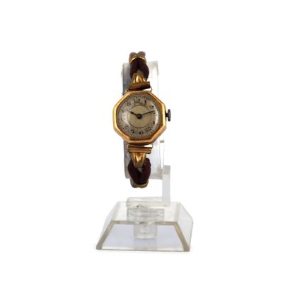 une montre en or posée sur un socle transparent, sur fond blanc