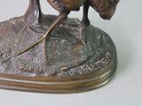 a bronze statue of a bird sitting on top of a rock