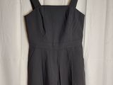 a black dress hanging on a hanger in front of a white curtain