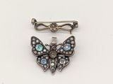 une image représentant une broche en forme de papillon ornée de pierres bleues