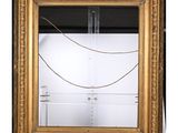 a gold framed mirror with a rope hanging from it ' s side