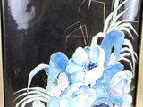 painting of blue flowers in a gold frame on a black background
