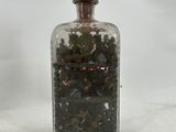 a glass bottle with a lot of small rocks inside of it