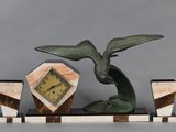 une statue représentant un oiseau avec une horloge, posée sur un socle