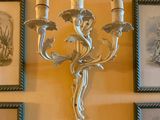 des tableaux accrochés au mur au-dessus d'un lustre à trois bougies
