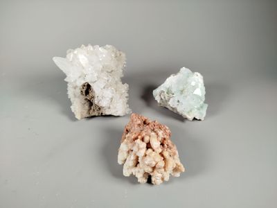 three different types of crystals on a gray surface