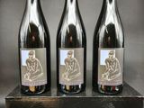 trois bouteilles de vin posées sur une caisse en bois