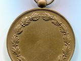 gold medal with a wreath of leaves and a ring on a white background