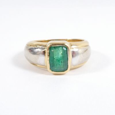 a close up of a gold ring with a green stone