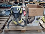 un aspirateur jaune et noir posé sur des palettes dans un entrepôt