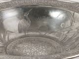 a silver bowl with a peacock design on it
