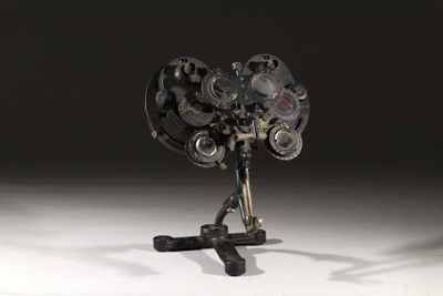 une sculpture représentant un ventilateur posé sur un trépied, sur une surface blanche