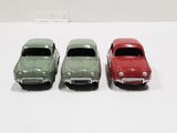 three toy cars are lined up in a row on a white surface