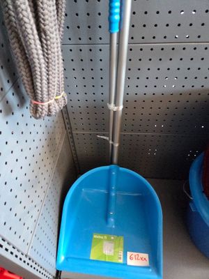a blue dust pan and a blue broom in the corner of a shelf