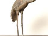 une statue en bronze représentant un oiseau posé sur une table