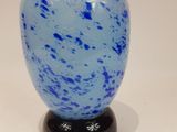 a blue vase with a black base on a white surface