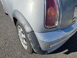 the rear end of a silver mini cooper parked on the side of the road