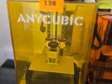 une imprimante 3D jaune posée sur une table, à côté d'une bouteille d'eau