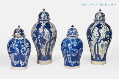 quatre vases bleus et blancs sont alignés sur un fond blanc
