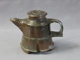 a small metal teapot with a lid on a table