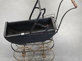 a black baby carriage with a wooden handle on a gray floor