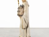 statue of a monk holding a basket and a pen in his hand