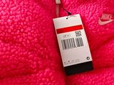 pink nike jacket with a tag attached to the back of it