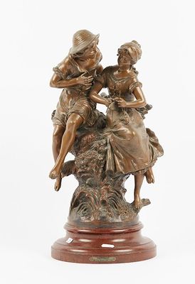 bronze statue of two women sitting on a rock