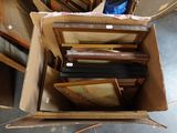 a cardboard box full of framed pictures on the floor