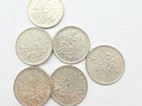 six different british coins sitting on top of each other on a white surface