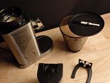 a coffee maker, a cup, and a coffee grinder on a wooden table