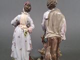 pair of porcelain figurines of a man and a woman standing next to each other