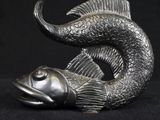 a statue of a fish that is sitting on a black surface