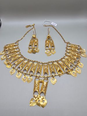 un collier et une paire de boucles d'oreilles en or posés sur une table