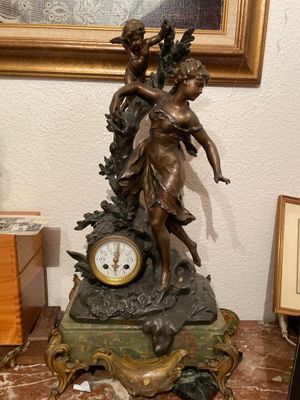 une statue de femme tenant une horloge sur une table