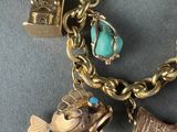 an image of a gold bracelet with charms and a fish